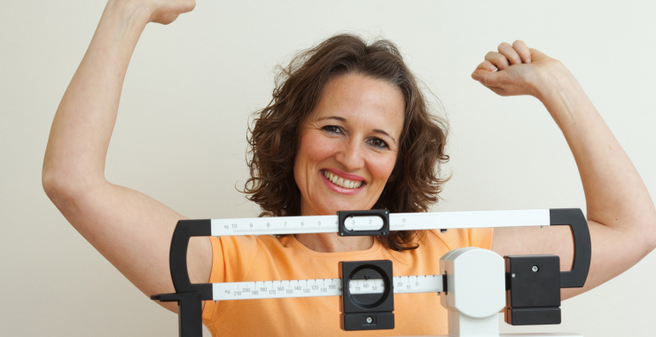 Woman standing in victory pose on scale